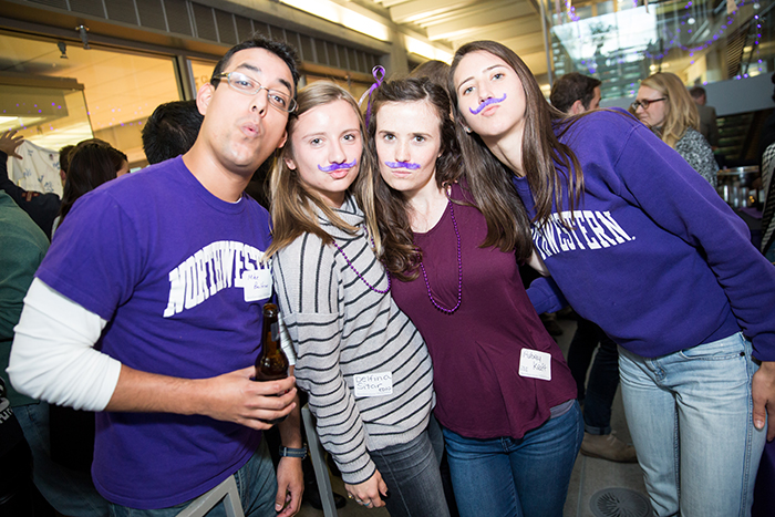 EDI Professor Mike Beltran poses with EDI students Delfina Sitar, Aubrey Kraft and Ellie Pearlman who are rocking their purple mustaches.