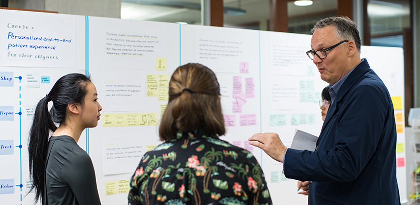 Professor Greg Holderfield (right) speaks with EDI students during a Design Strategy class.