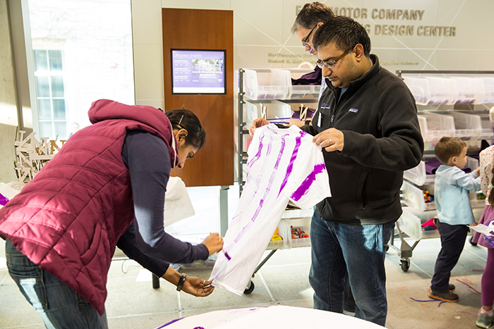 MMM student Shriansh Shrivastava and his wife paint white t-shirts to give them some extra purple homecoming flair. 